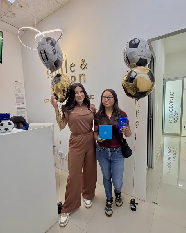 La doctora y una paciente celebran el inicio del tratamiento, con globos y la caja de Invisalign