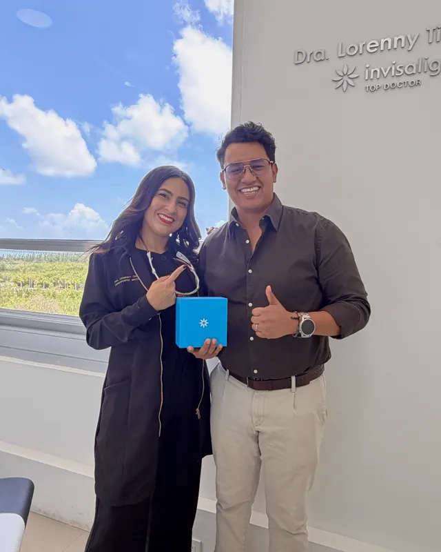 Un paciente levanta el pulgar junto a la doctora, con su caja de Invisalign